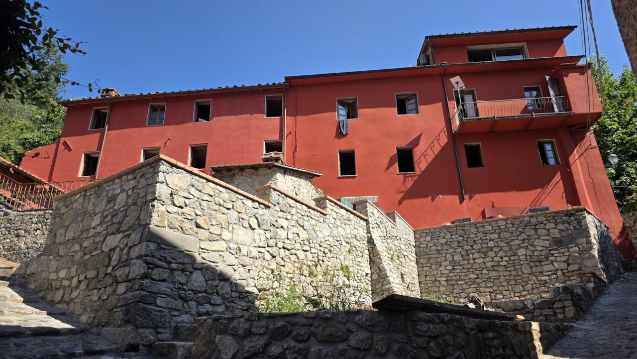 Main red facade of the Vallico Academy buildings above the stone terraces